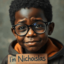 a young boy wearing glasses holds up a sign that says i 'm nicholas