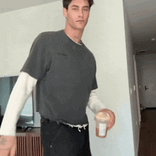a man wearing a grey t-shirt and black pants is holding a bottle of peanut butter