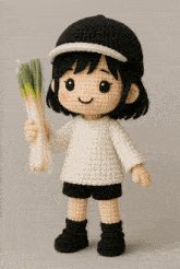 a crocheted doll wearing a white sweater and black shorts is holding a tennis racquet