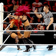 two women are wrestling in a ring while a referee watches