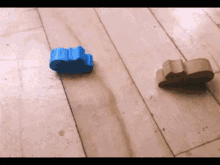 two pieces of wood are laying on a wooden floor one blue and one brown