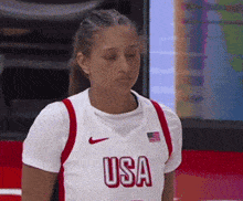 a female basketball player wearing a usa jersey looks down