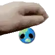 a hand is holding a small blue ball with a face on it .