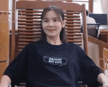a woman wearing a black shirt that says grunge but cute is sitting in a chair