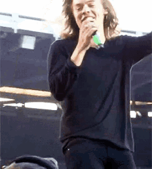 a man is singing into a microphone on stage .
