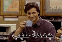 a man in a purple shirt is drinking from a blue mug with arabic writing