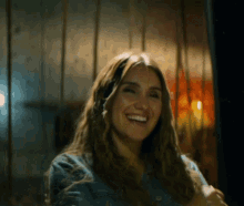 a woman with long hair is smiling and wearing a blue jacket