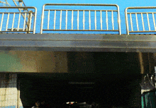 a bridge with a railing and a blue sky behind it