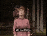 a woman in a red dress sings with the words " we lose things " on the screen behind her