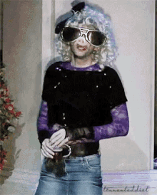 a woman wearing sunglasses and a wig is standing in front of a wall with the word teenaladaddict written on the bottom
