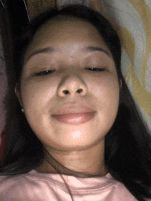 a close up of a woman 's face with her eyes closed and a pink shirt on