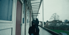 a man in a black hooded jacket is walking down a hallway