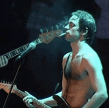 a man smoking a cigarette while playing a guitar and singing into a microphone