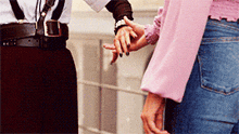 a woman in a pink shirt holds the hand of a man in suspenders