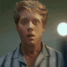 a man with a surprised look on his face is wearing a grey shirt