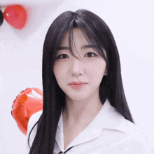 a woman with long black hair and a white shirt looks at the camera