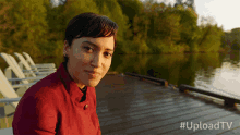 a woman is sitting on a dock with the hashtag uploadtv
