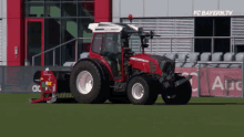 a large red tractor is parked in front of a building that says fc bayern.tv