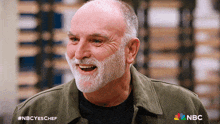 a man with a beard is smiling with the nbc logo on the bottom right
