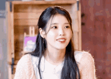 a woman with long black hair is wearing a pink sweater