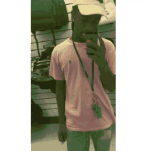 a man wearing a pink shirt and a white hat takes a selfie with his phone