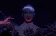 a man with blue paint on his face surrounded by hands