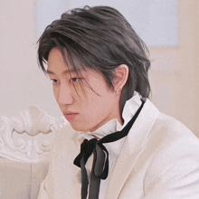 a man wearing a white suit and black tie