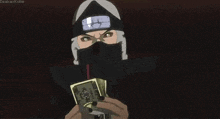a man in a ninja costume is holding a stack of money and playing cards .