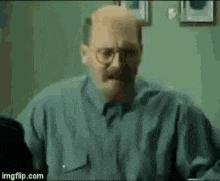 a bald man with glasses and a mustache is sitting at a desk .