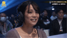 a woman wearing headphones is smiling in front of a sign that says mirai on it