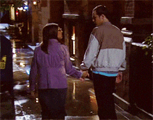 a man and a woman are holding hands while walking down a street