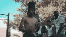 a group of men are standing around a basketball hoop including a shirtless man wearing a black turban