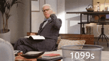 a man in a suit sits on a couch reading a book with 1099s written on the bottom right