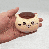 a person is holding a toy in their hand that looks like a cat with a brown hat on .
