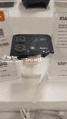a broken redmi phone is displayed on a stand