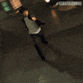 a man in a suit is jumping in the air with the hashtag #karatekidmovie behind him