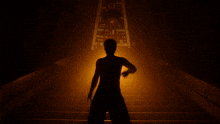 a person standing on a set of stairs with their arms outstretched in the dark