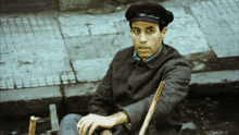 a man in a hat sits on a chair on the sidewalk