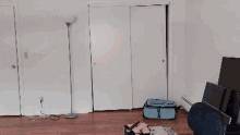 a man is dancing in an empty room with a blue suitcase in the background
