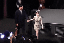 a man in a suit and tie holds a woman 's hand