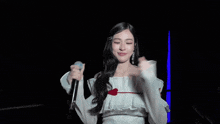 a woman in a white off the shoulder top holds a microphone