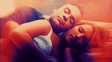 a man and a woman are laying on a bed with their heads on each other