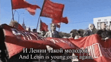 a group of people holding red flags with the words " and lenin is young once again "