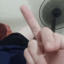 a person giving the middle finger with a fan behind them