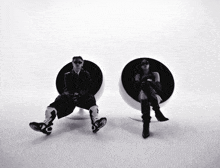 a black and white photo of a man and a woman sitting on chairs