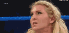 a close up of a woman 's face in a wrestling ring with a blue background .