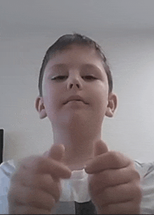 a young boy is making a funny face while holding a piece of paper in his hands .