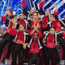 a group of women in red and black outfits are performing on a stage in front of a sign that says got talent