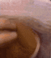 a close up of a cup of coffee with a pink blanket in the background