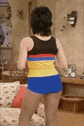 a woman is standing in a living room wearing shorts and a tank top .